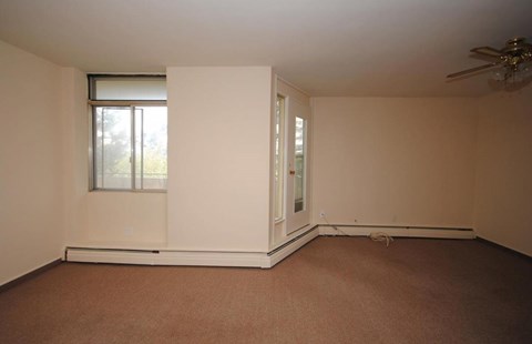 A room with a brown carpet and a ceiling fan.