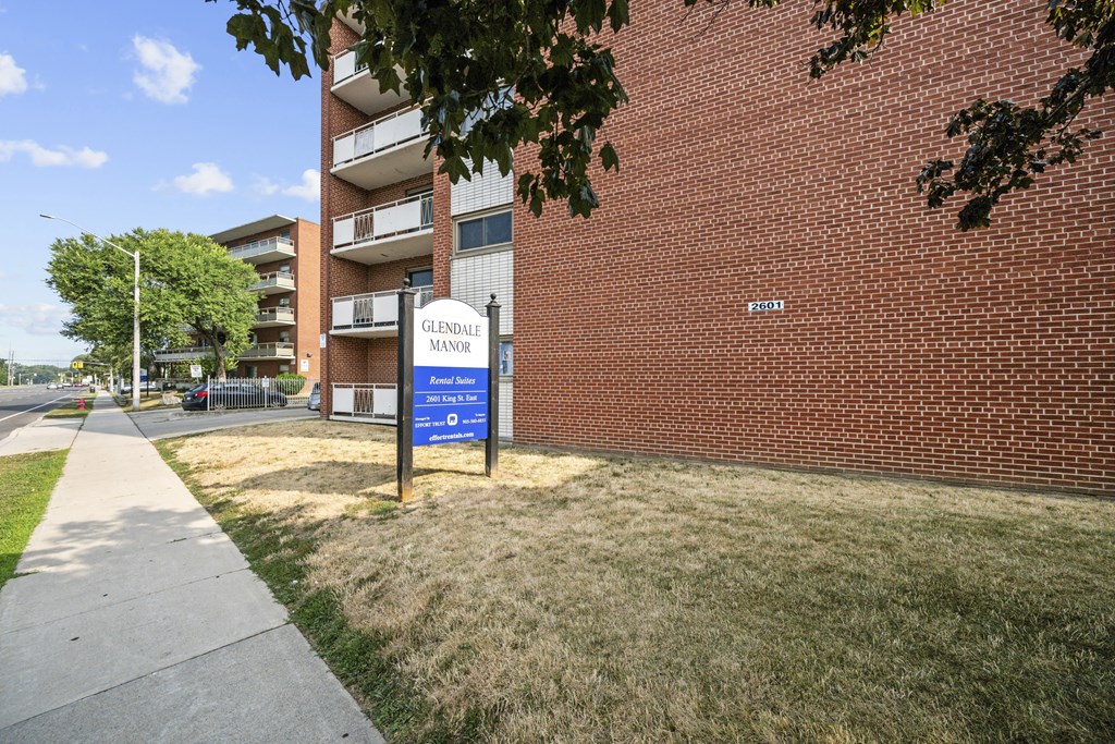 A sign for Glendale Manor Apartments stands in front of a brick building.