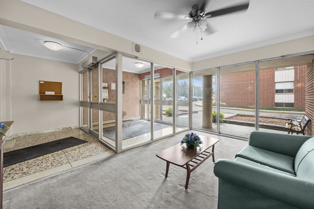 A living room with a green couch, a coffee table, and a ceiling fan.