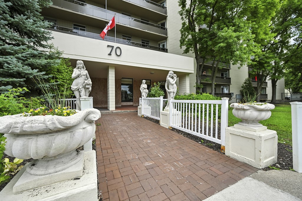 A building with the number 70 on it has a white fence and statues on it.