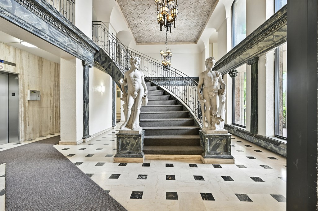 A staircase with a chandelier and statues on either side.