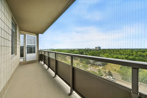 A balcony with a view of a parking lot and trees.