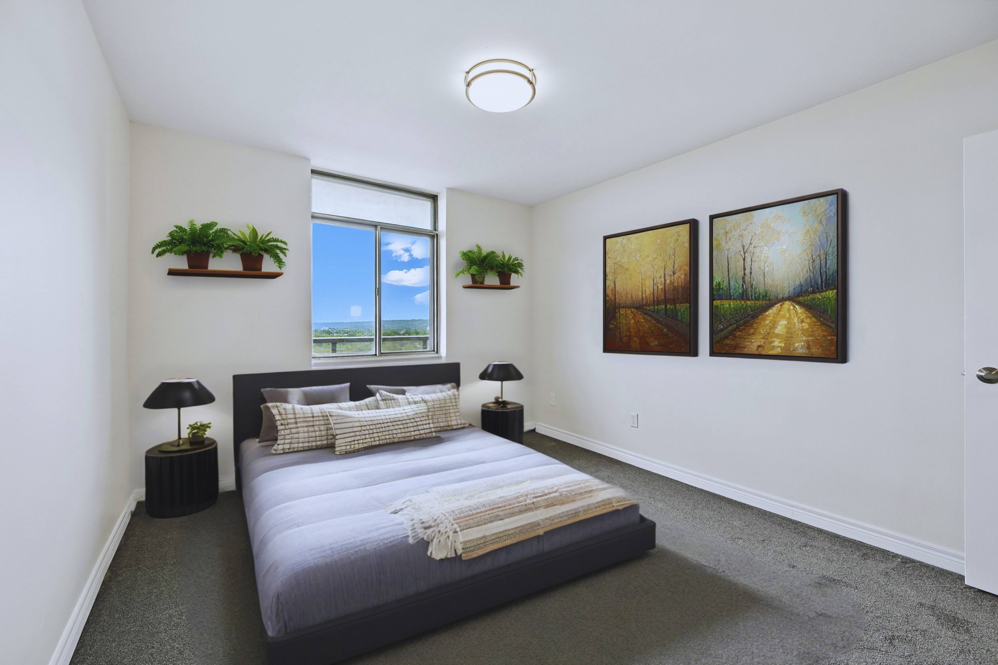 A bedroom with a large bed and two paintings on the wall.