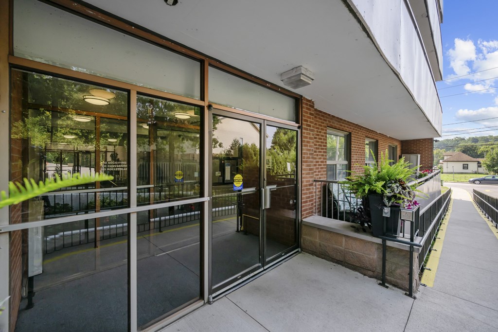 A building with a glass door entrance and a balcony with potted plants.