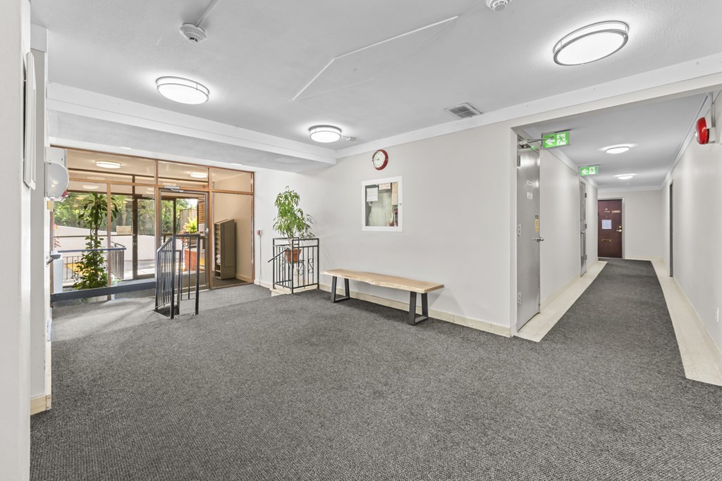 A long hallway with a bench and a fire extinguisher.