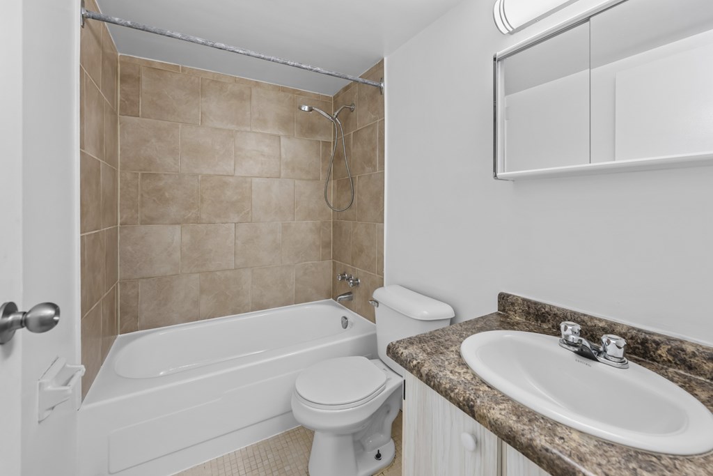 A white toilet sits next to a bathtub in a bathroom.