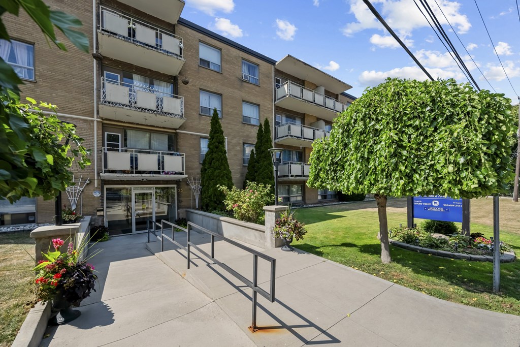 A sunny day at a residential building with a blue sign in the front yard.