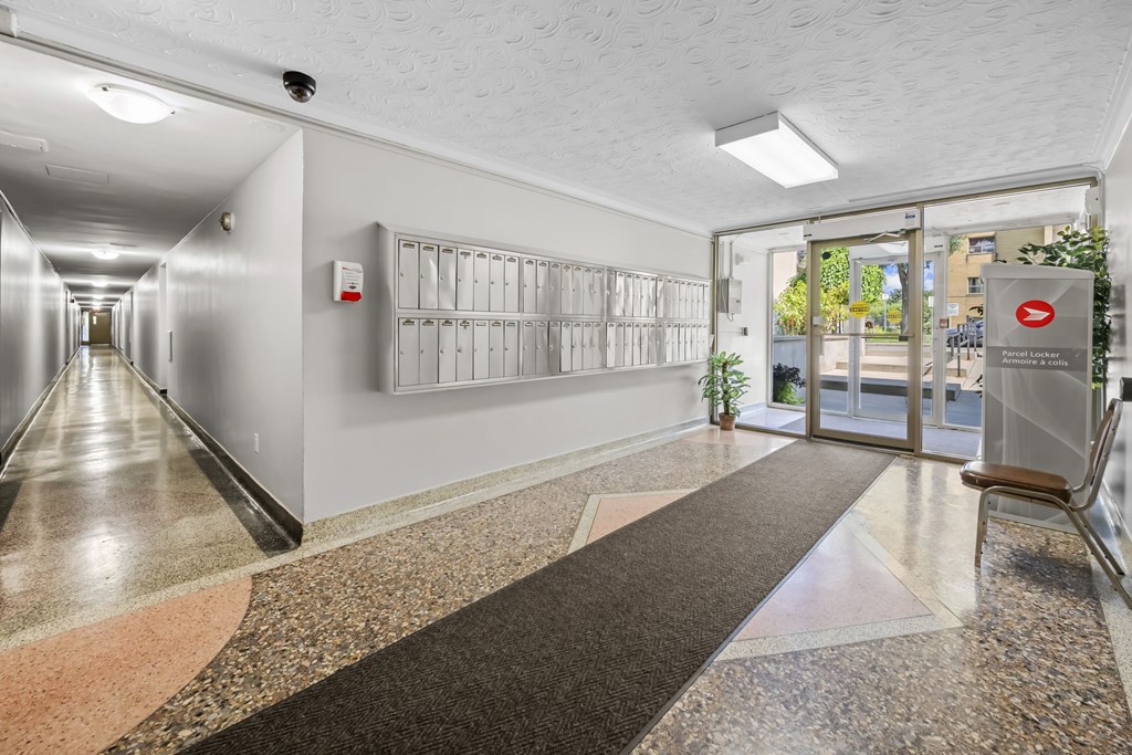 A long hallway with a red exit sign on the wall.