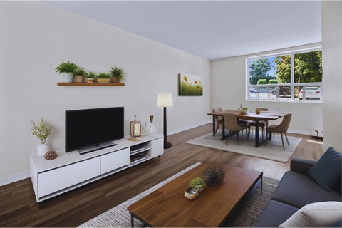 A living room with a television, a couch, a coffee table, and a dining table.