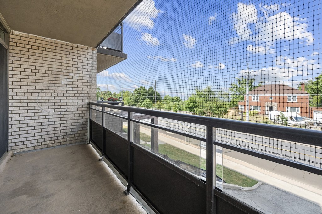 A balcony with a black railing and a brick wall.