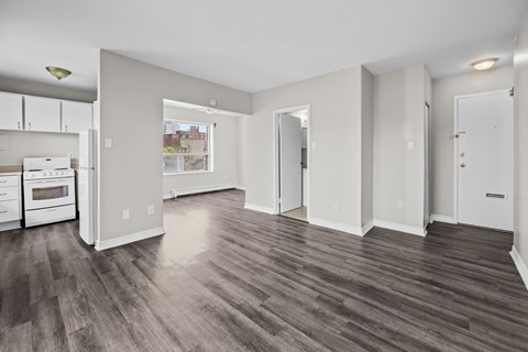 A spacious living room with wood flooring and white walls.