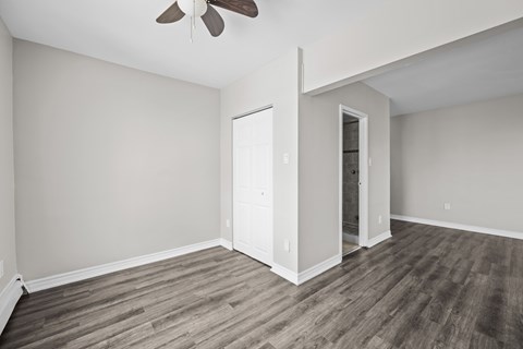 A room with a ceiling fan and wood flooring.