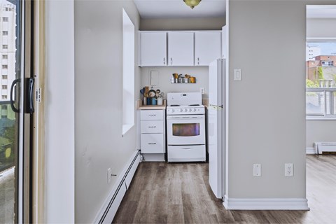 A kitchen with white appliances and wooden floors.