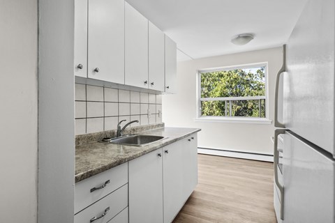 A kitchen with white cabinets and a window.