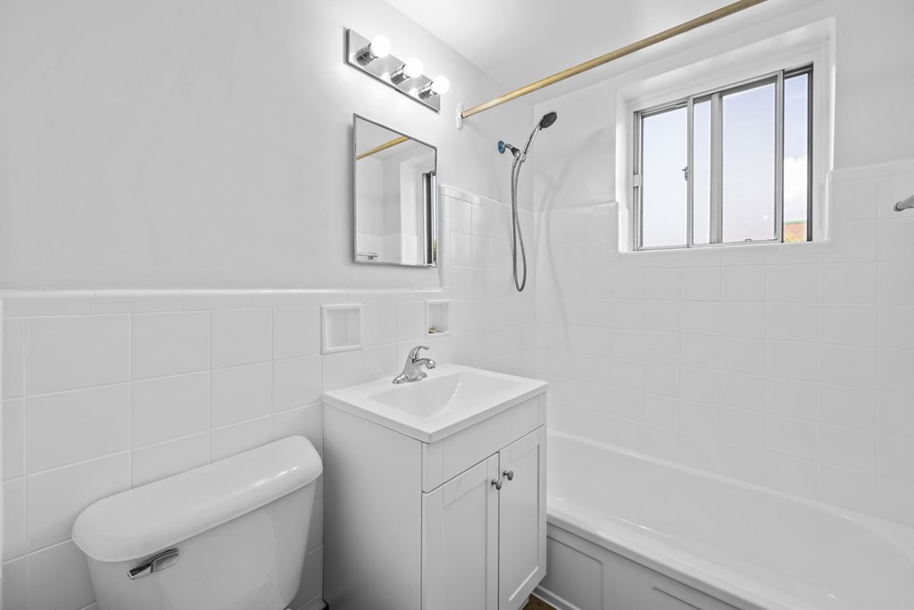 A white bathroom with a tub, sink, and mirror.