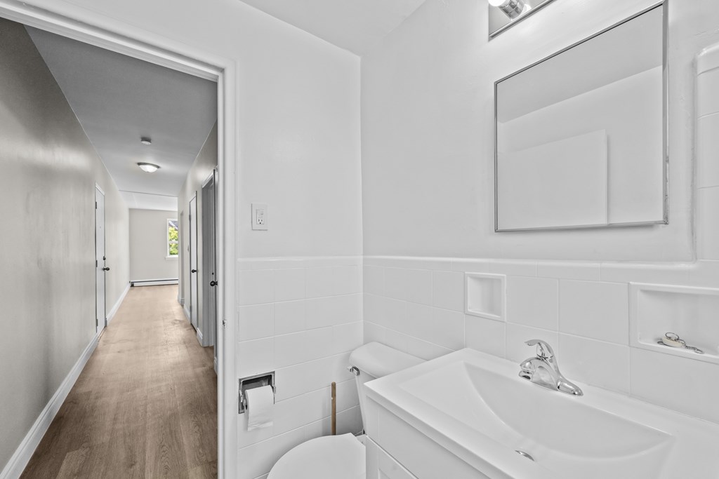 A white bathroom with a sink, toilet and mirror.