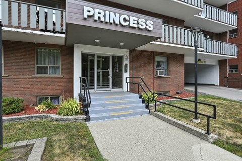 The entrance to a building named Princess with a glass door and steps leading up to it.