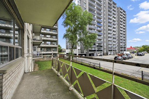A view of a balcony with a metal railing and a building in the background.