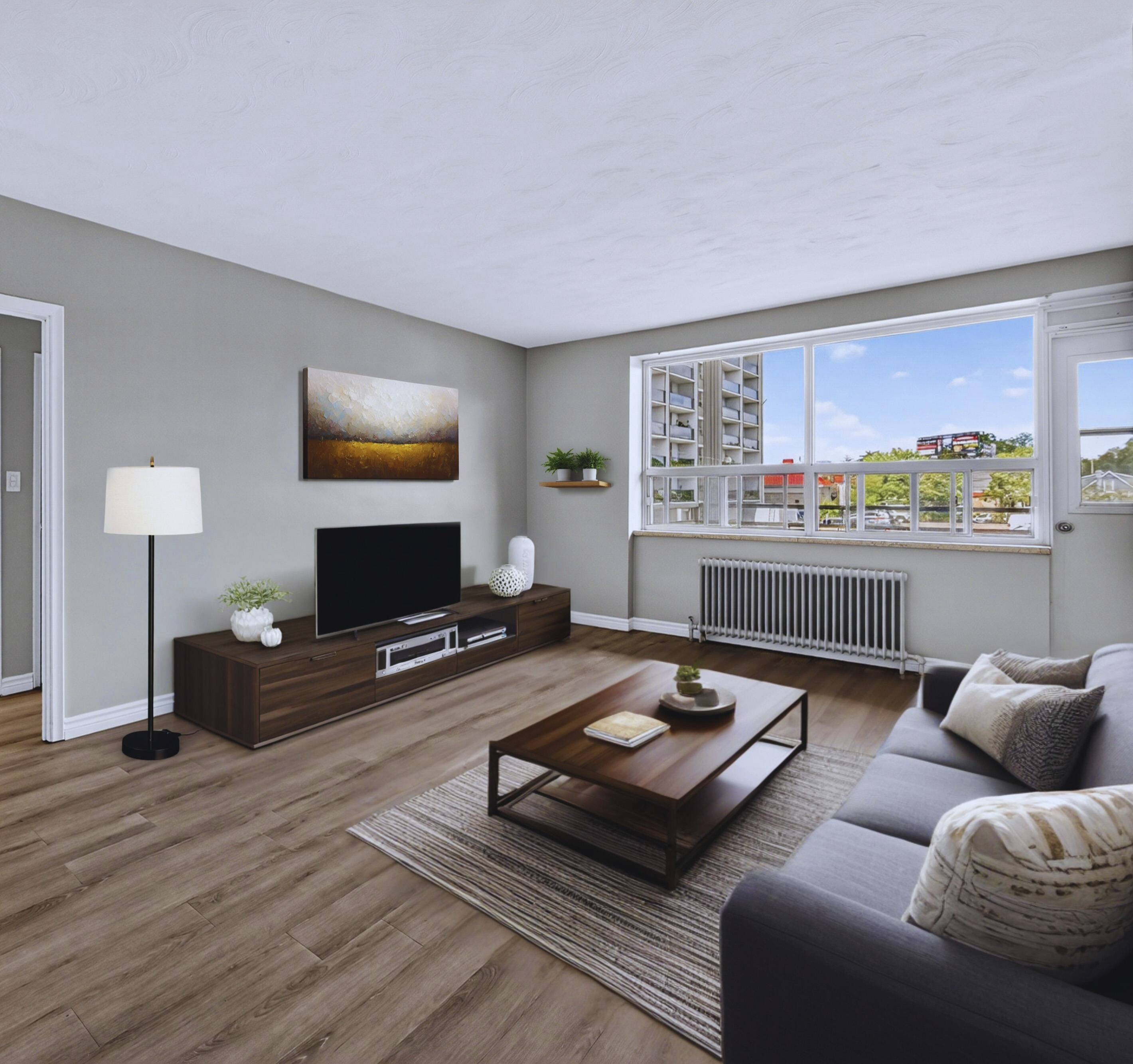 A living room with a grey couch, a wooden coffee table, and a television on a stand.