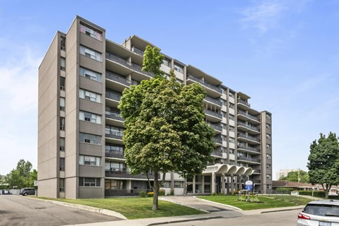 A large apartment building with a tree in front of it.