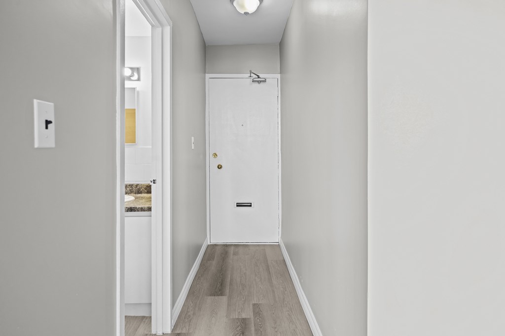 A white door with a black handle is in the middle of a hallway.