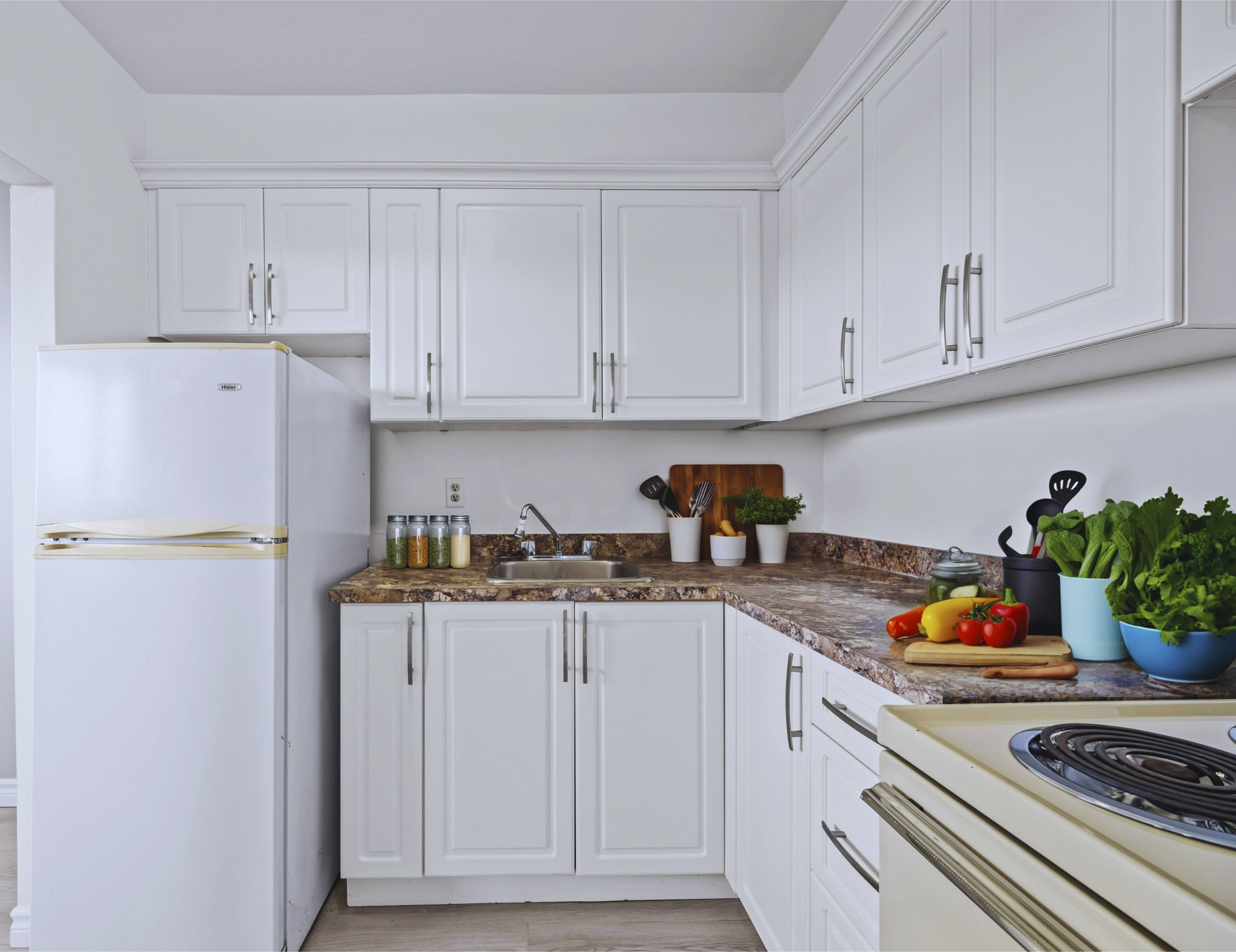 A kitchen with white cabinets and a marble countertop.