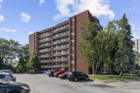 A large red brick building with a parking lot in front.