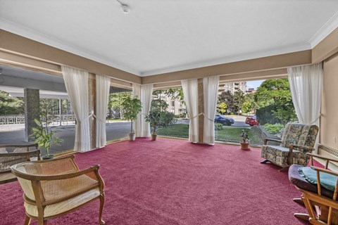 A room with a red carpet and a wooden chair.