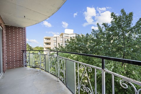 A balcony with a metal railing and a view of apartment buildings.