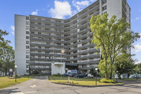 A tall building with a flag on top and a tree in front.