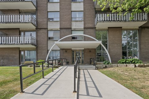 A modern building with a white arched entrance and a metal railing.