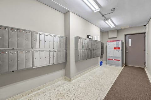 A hallway with a row of lockers on the left and a door on the right.