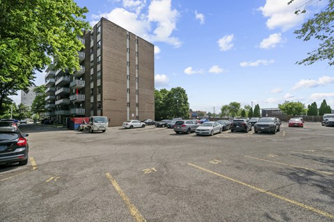 A parking lot with cars and a tall building in the background.