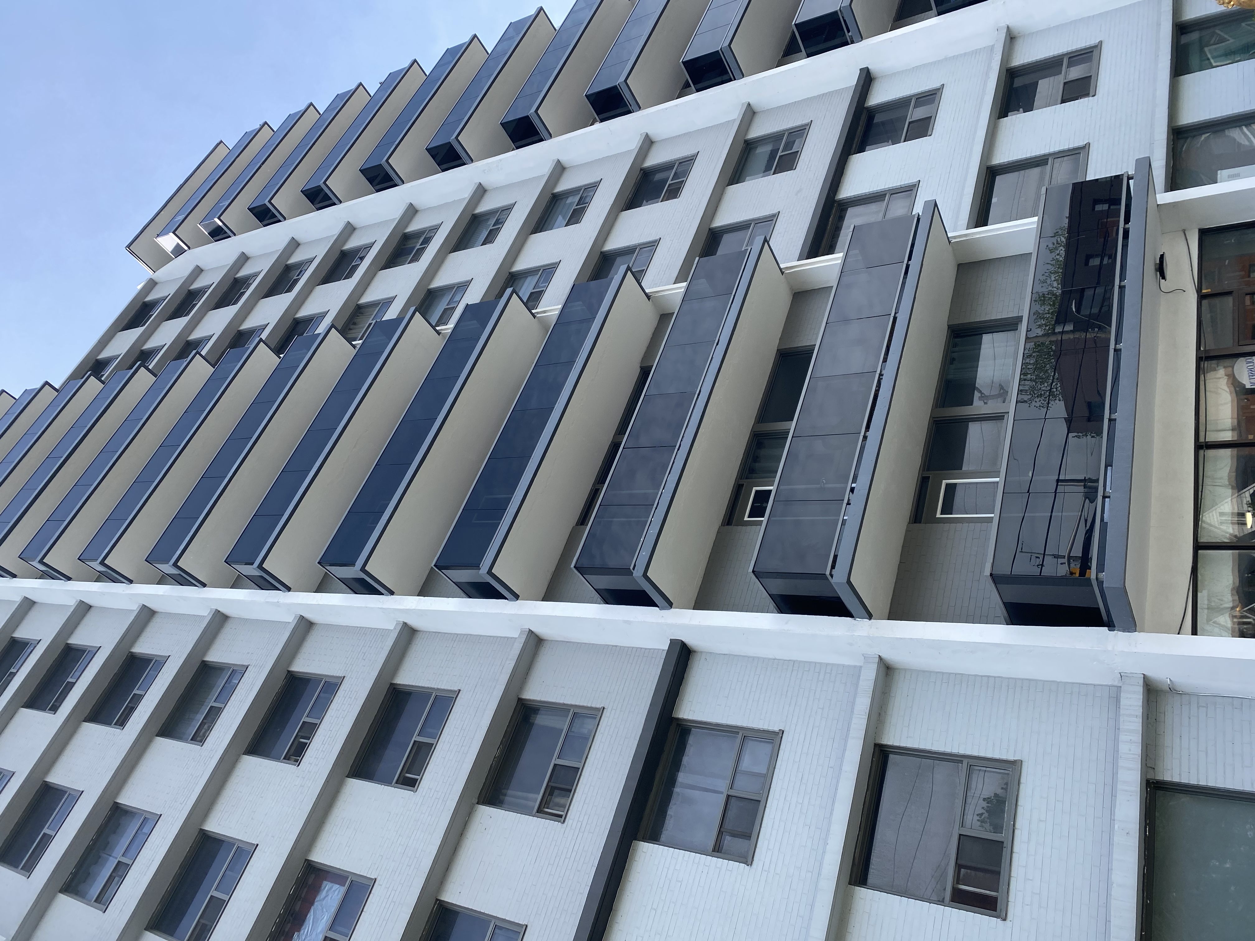 A modern building with a white facade and black balconies.