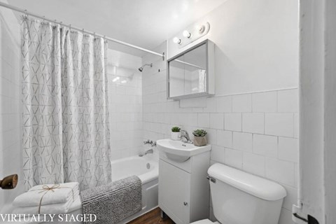 A white bathroom with a tub, sink, and mirror.