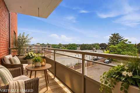 balcony with a table and chairs overlooking a parking lot.
