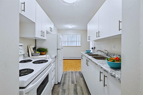 A kitchen with white cabinets and a wooden floor.
