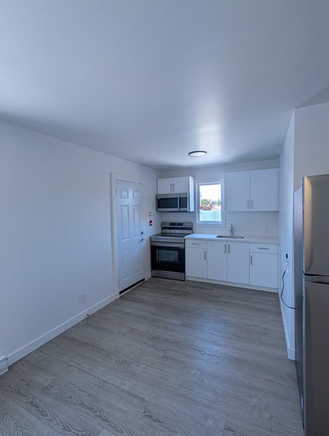A kitchen with white cabinets and a refrigerator.
