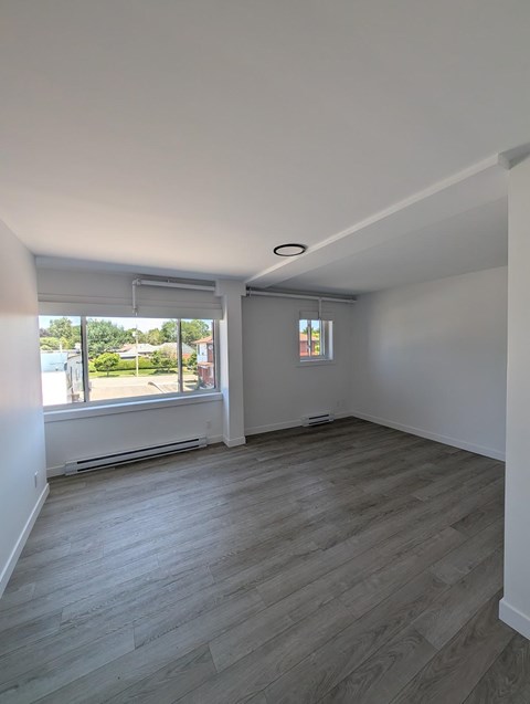 A room with a window and a wooden floor.