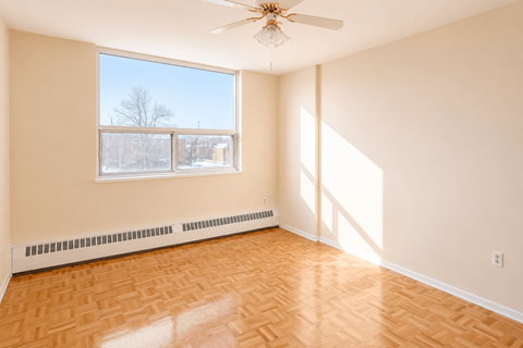 A room with a ceiling fan and a window showing a view of a tree.