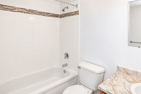 A white toilet sits next to a bathtub in a bathroom.