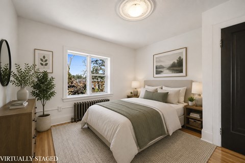 A bedroom with a large bed and a window overlooking a tree.