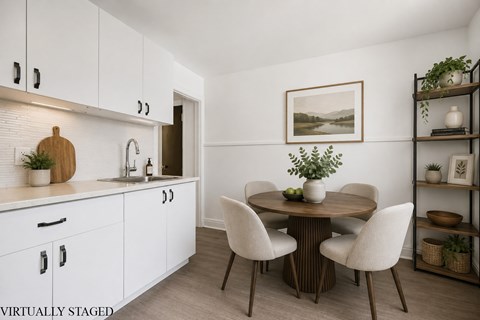 A kitchen with white cabinets and a wooden table with chairs.