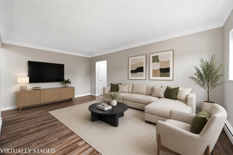 A living room with a white couch, a black coffee table, and a wooden floor.