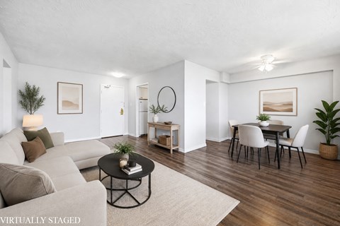 A living room with a white couch, a coffee table, and a dining table with chairs.