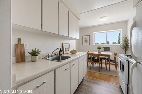 A kitchen with white cabinets and a wooden table.