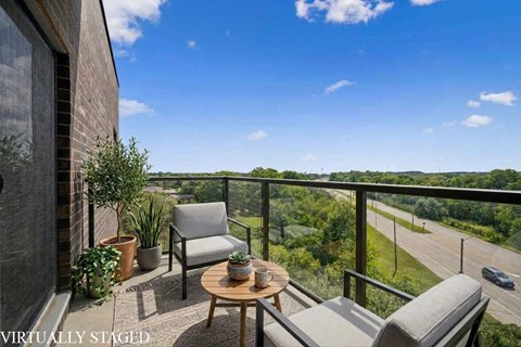 A balcony with a table and chairs overlooking a highway.
