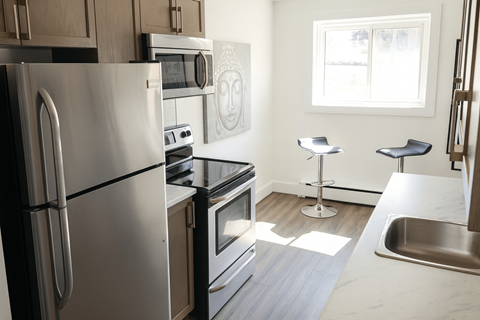 A modern kitchen with stainless steel appliances and a marble countertop.