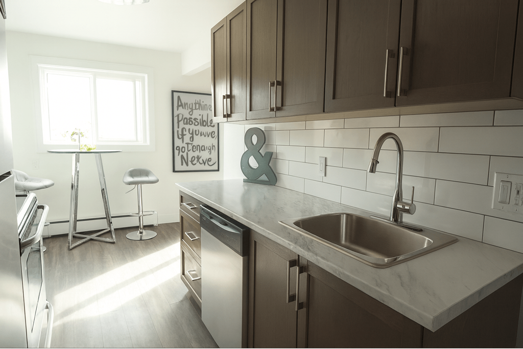 A kitchen with a white tiled backsplash and a stainless steel sink.