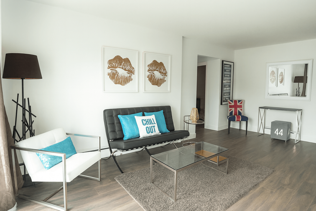 A living room with a black couch and a white chair.